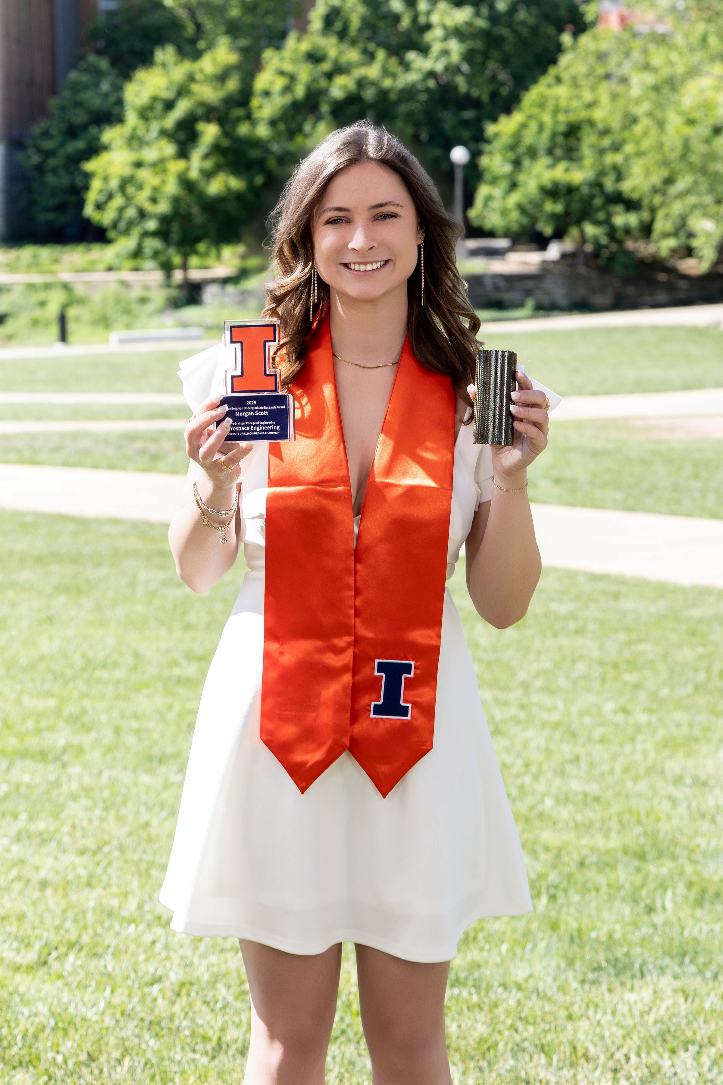 Morgan Scott holding the Lawrence Bergman Undergraduate Research Award and one of the composite tubes she manufactured while working the Composites and Additive Manufacturing Lab on campus.
