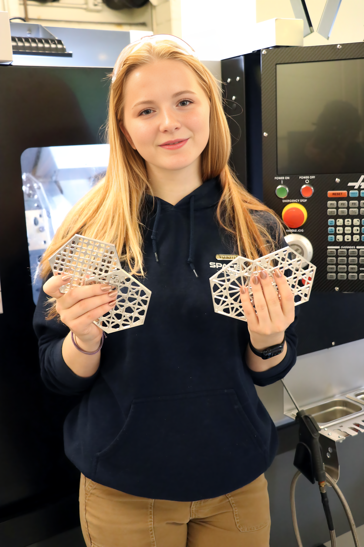 Amber Parker holding a set of coasters she made in Dustin Burns' machining course.