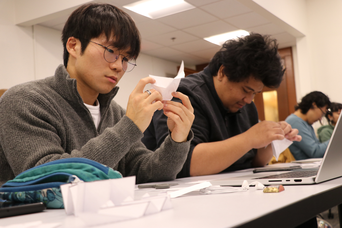 two students working on origami project in class