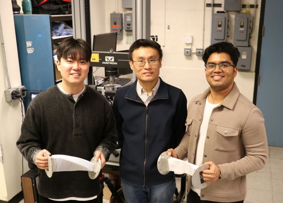 Aerospace graduate students, Sangwoo Suk and Nikhil Ashok, holding origami-inspired waveguides. Between them is Xin Ning, professor in the Dept. of Aerospace Engineering.