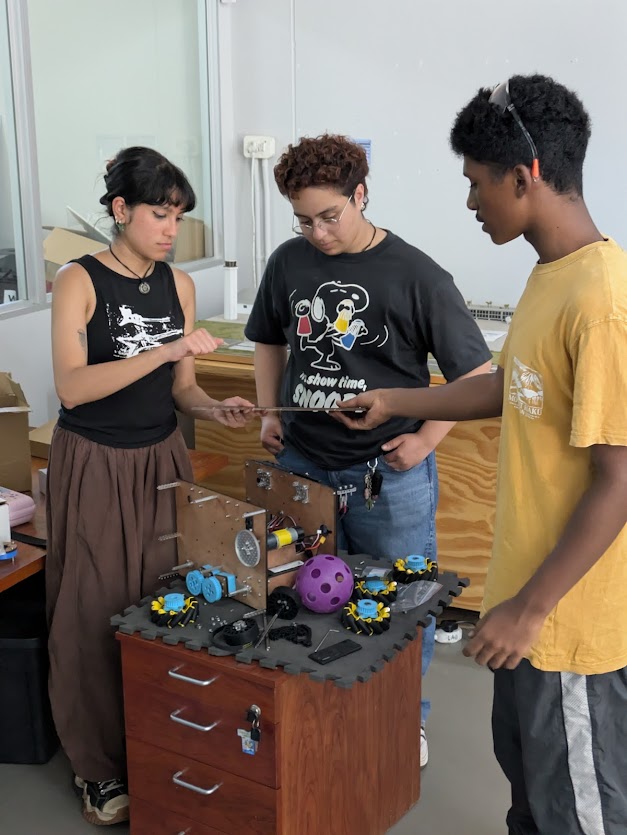 Aalia Angirish, Aljawan Abdulrahim, and a recent graduate from Cape Academy of Mathematics, Science and Technology. He is part of their First Robotics Team, Team Astrovo, Instagram @astrovo_ftc.   They are checking out the team robot for this year.