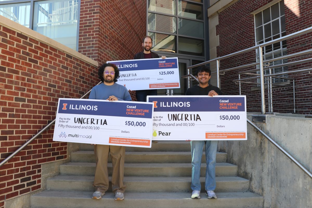 On the north steps of Talbot, Melkior Ornik holds the big $25K check at the top, Gokul Puthumanaillam holds the $50K check from Multimodal and Manav Vora holds the check for $50 from Pear VC.