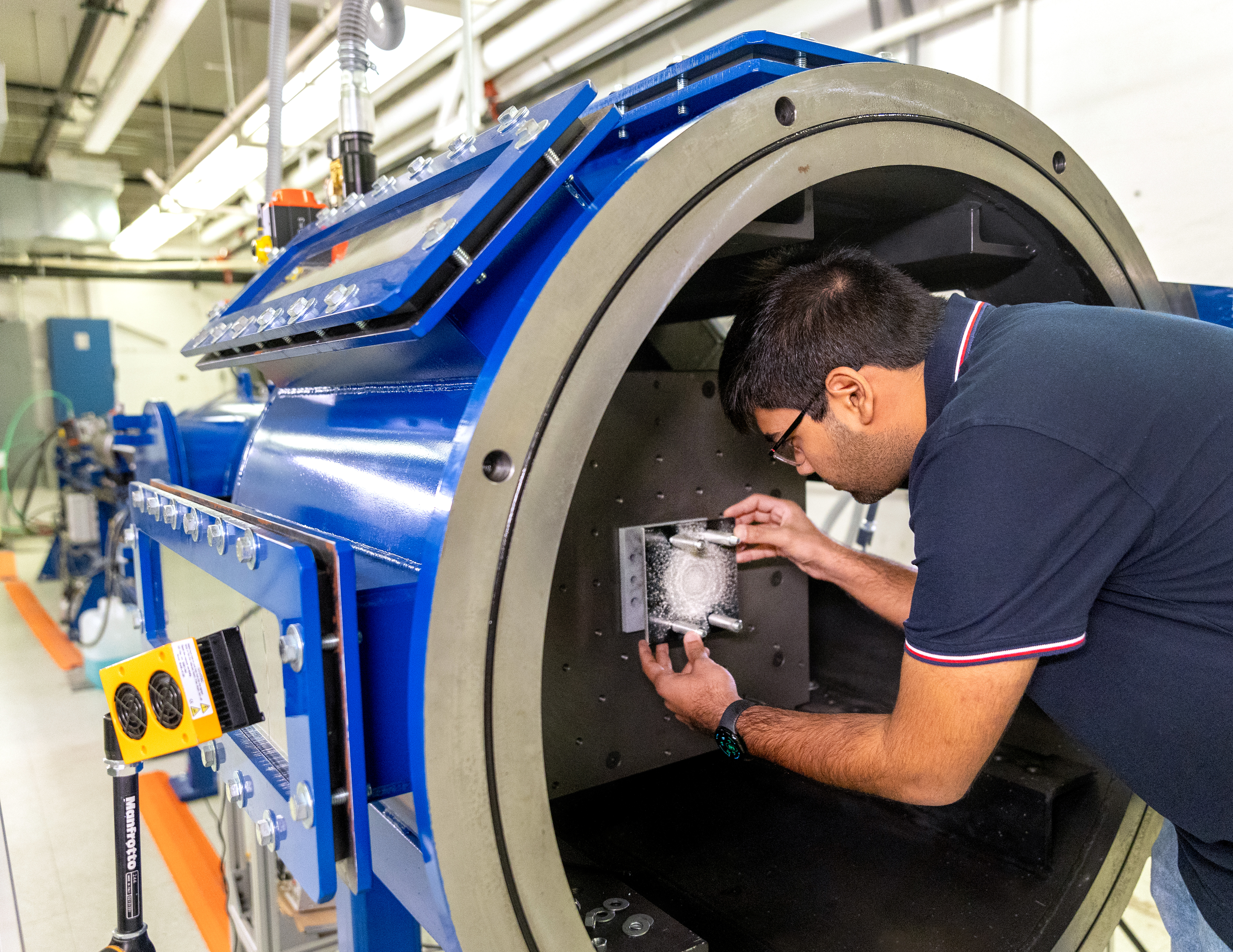 After running an experiment, Anshul Agrawal takes the witness plate out of its mount inside the gun. The plate shows the damage produced by the debris cloud produced by the impact.