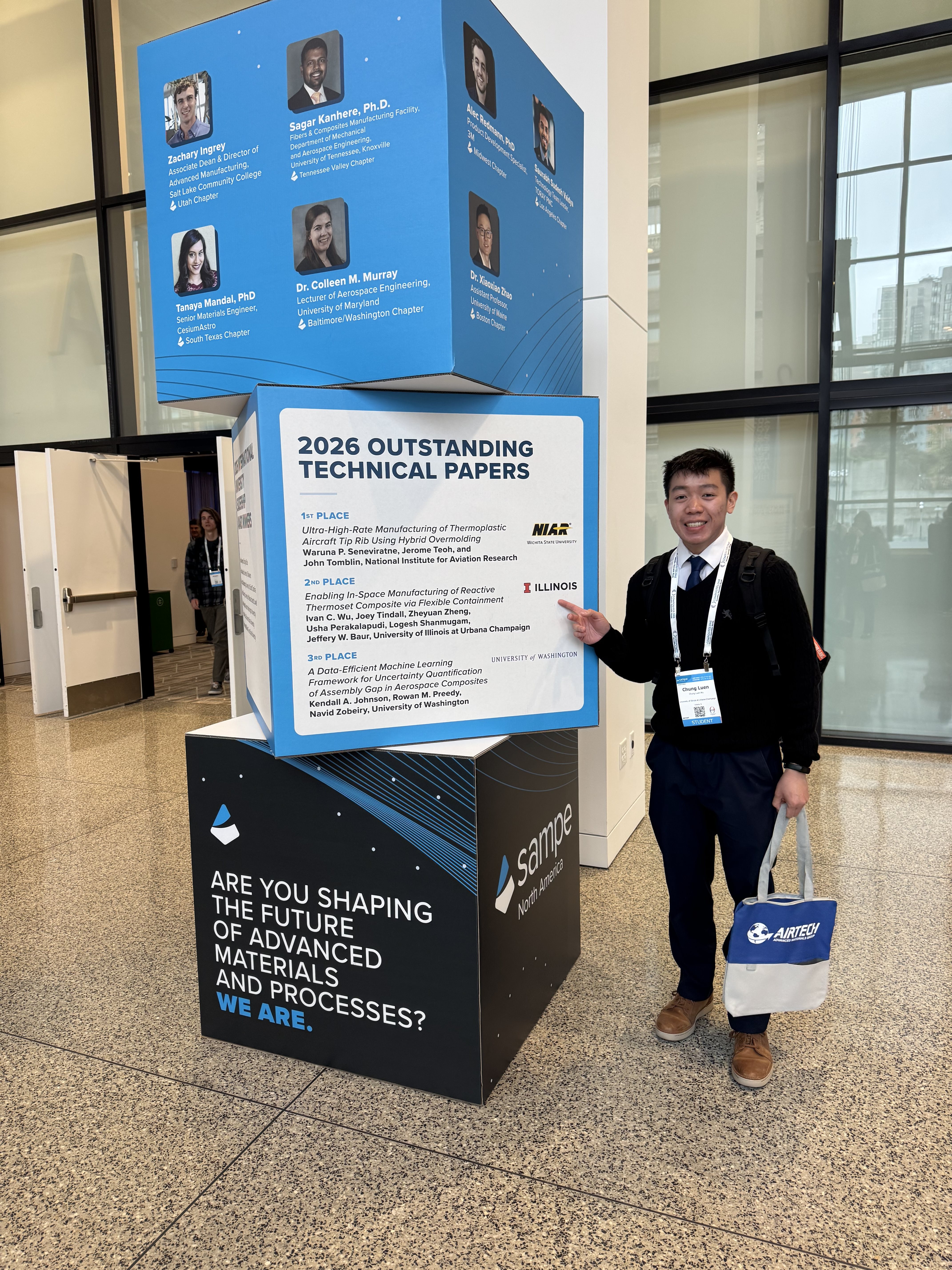 Ivan Wu standing next to a sign listing his award for 2nd place in the Best Paper.