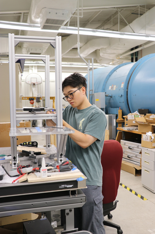 Benedict Benvito Themas working on the test stand in Saxton-Fox' lab.