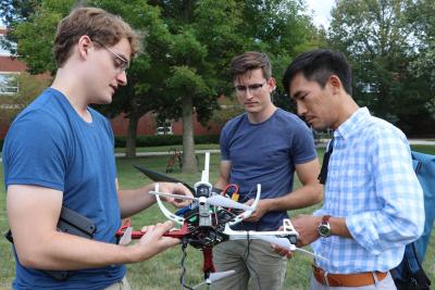 Photo taken in 2019 of (left to right)  Neale Van Stralen, Ayberk Yaraneri, and Huy Tran testing a drone on the U of I campus.