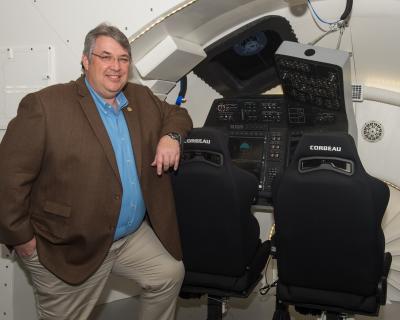 Michael J. Burghardt with original CST-100 Starliner Crew displays and controls mock-up