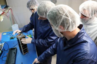 In the University of Illinois clean room lt to rt: Ravi Patel, Adam Newhouse, Dillon Hammond, Nick Zuiker (white lab coat) aerospace engineering team leader for the CubeSat SASSI2, a joint project between U of I and Purdue University.