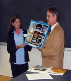 Cathy Larson Koerner presenting a montage of Mission Control photos, including a 2007 Atlantis patch, to AE Department Head Craig Dutton.
