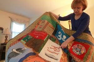 Philip Patnaude's mother, Phyllis, displaying the quilt that commemorates her son. One of the quilt patches was made from a T-shirt saying that Philip flew solo while at the University of Illinois.