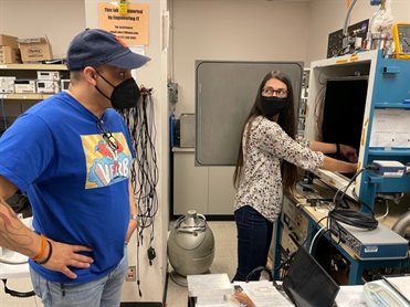 AE undergraduate Chris Young and graduate student Michelle Zosky prepare the thermal vacuum chamber for testing material samples which were heated in vacuum for 24 hours and monitored by a computer system that tracked pressure and sample temperature.