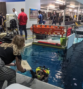 Harriet Hunt hands her team's lunar sample collection bag system to a diver.