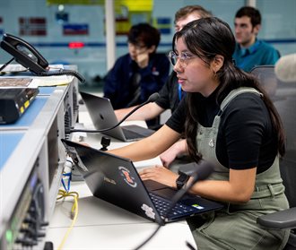 Aliah Rubio in the control room communicating her team's test operational plan to the in-water NBL diver testing the tool they created.