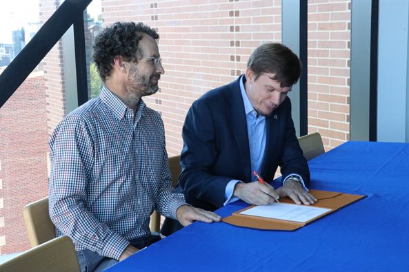 AE Professor and Dept. Head Jonathan Freund watches as Boeing's Vice President of Sustainability and Future Mobility James Hileman takes his turn signing a pledge of support.