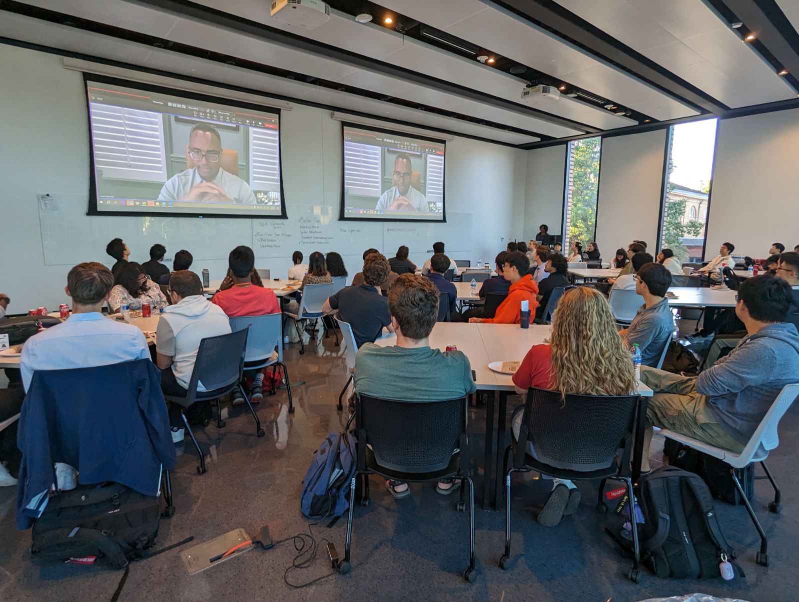 Derek Smith on large screens giving a career talk to Illinois students via Zoom as part of PwCâ€™s information session during a recruiting event.