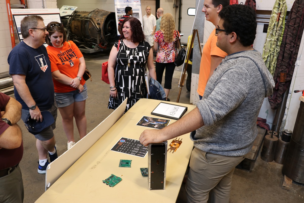 Traci Elving with husband Craig and daugher Vicki talking with students at an aerospace exhibit.