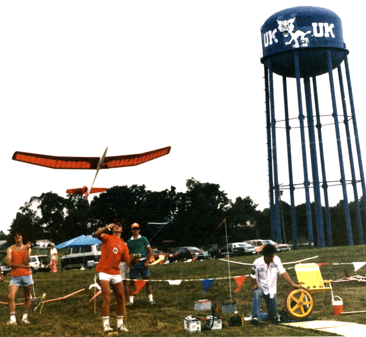 Photo from the early 1980s of Michael Selig winch launching his Airtronics Sagitta 900 at an RC sailplane contest at the University of Kentucky Lexington. The person on the right is managing the winch line that runs out to a pulley several hundred feet away and then back to the sailplane towhook. Selig is operating the winch with a foot pedal.